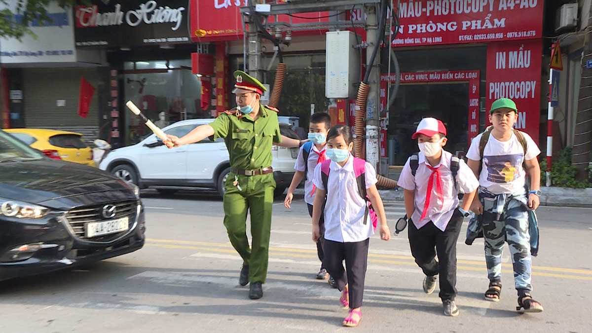Hình ảnh ấm áp về chú cảnh sát giao thông đang dẫn học sinh qua đường.