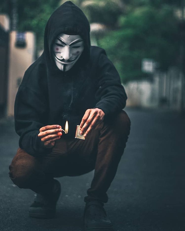 Hình hình ảnh Anonymous đang được nạm que diêm châm lửa.