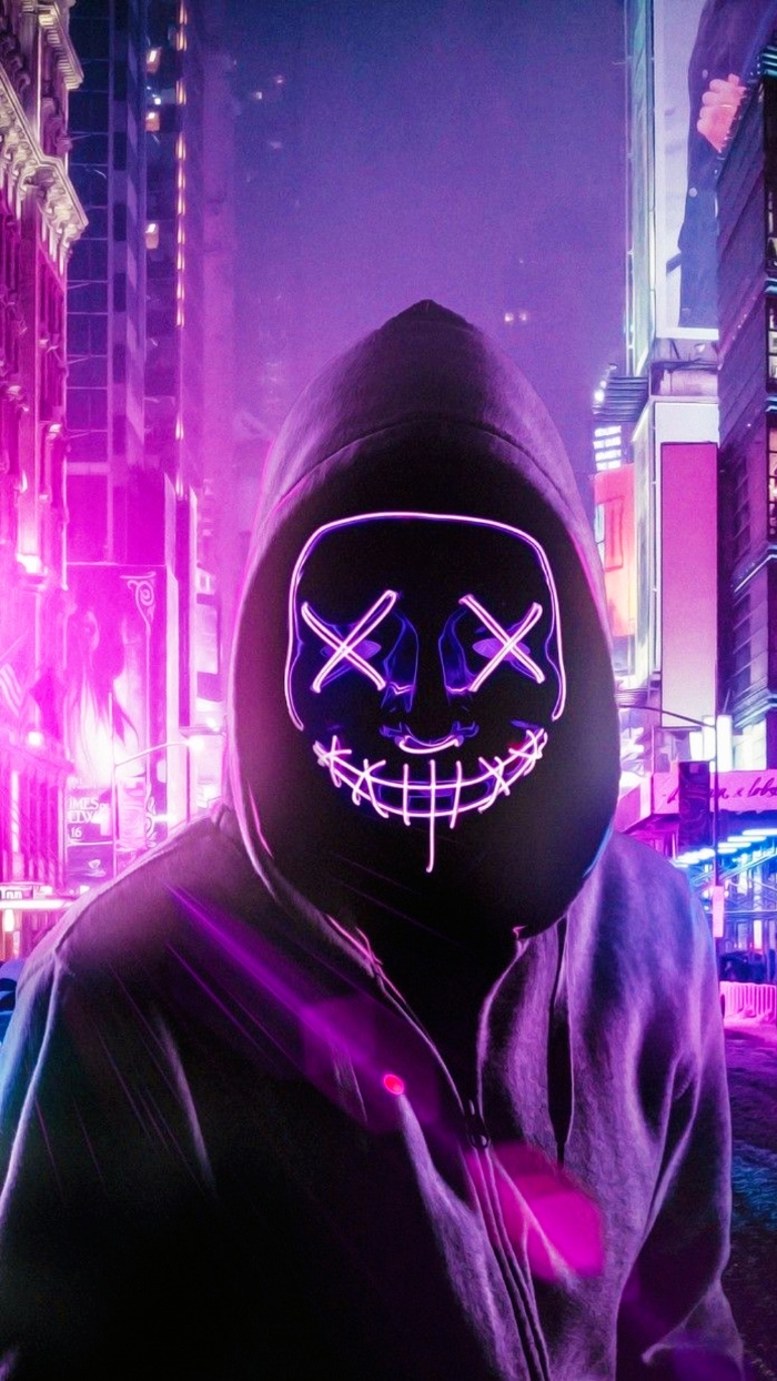 Anonymous avatar neon 7 màu đang tạo dáng dưới thành phố tương lai.