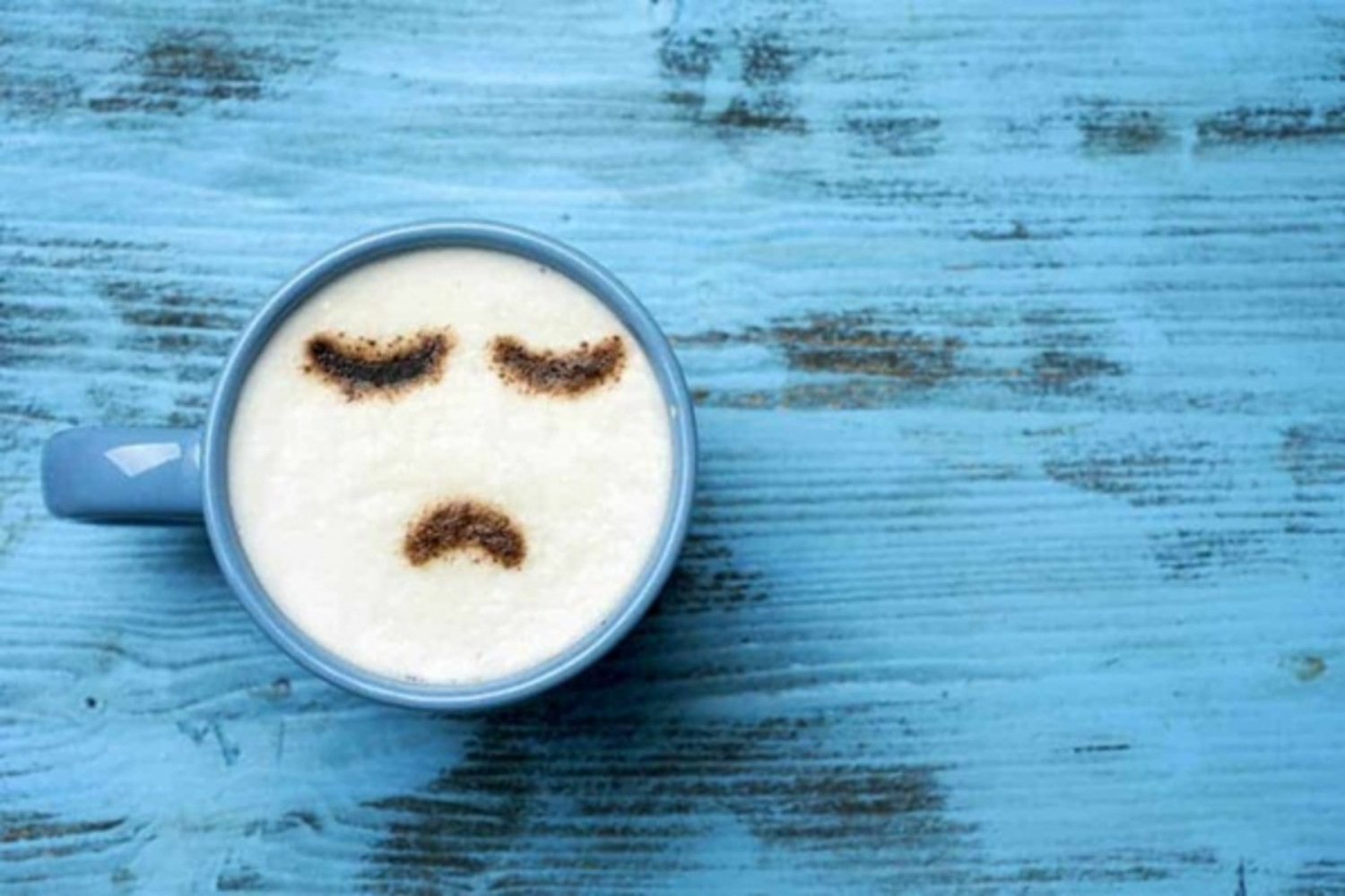 Hình ảnh ly cà phê màu xanh có hình mặt buồn. :((